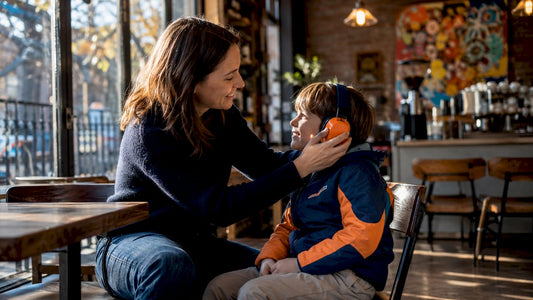Mother fitting ear protection on young boy indoors